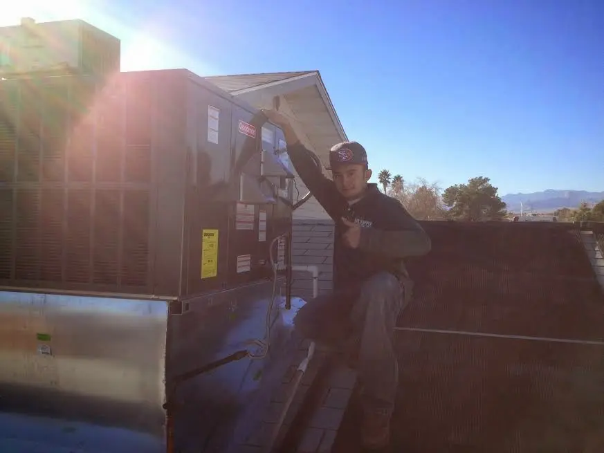 HVAC technician performing Air Duct Cleaning on a rooftop unit in Roanoke